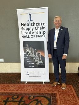 Jake Groenewold, Bellwether Class of 2021, next to BLF's Healthcare Supply Chain Leadership Hall of Fame sign.