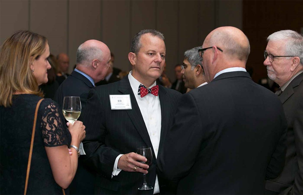 Beaumont Health’s Ed Hardin (center) talks with (left to right) Vizient’s Molly Matthews, Mike McMahon (back to camera) and Mike Duke. Mercy’s Vance Moore and New York-Presbyterian’s Anand Joshi, M.D., talk behind them.